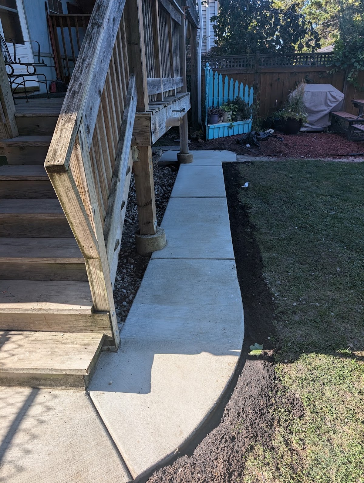 Curved concrete walkway beside wood porch stairs